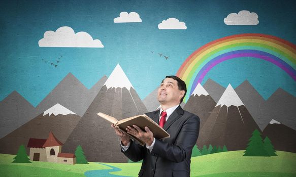 Happy businessman holding open book. Portrait of smiling adult man in business suit and tie standing on background of nature landscape with mountains and rainbow illustration. Education and knowledges