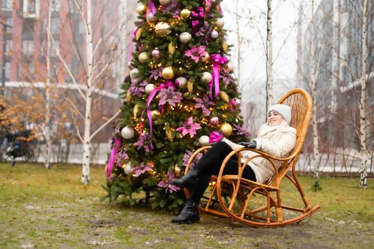 woman and photo zone christmas tree and rocking chair on the street