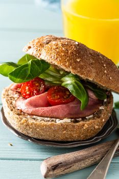 Sandwiche with beef, fresh tomatoes and lamb's lettuce, multigrain bun on blue wooden background. Healthy lunch concept