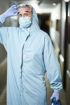 Worker wearing a protective mask, gloves and suit before disinfection in hotel. Coronavirus and quarantine concept