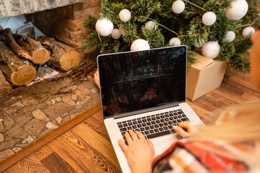 Happy woman looking in laptop in front of Christmas tree