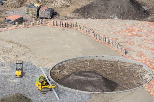 Improvement of the courtyard paving slabs, unfinished work on laying paving slabs. Laid new paving slabs sprinkled with sand and heaps of figured tiles ready for installation