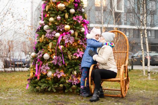 Smiling mother and daughter near Christmas tree