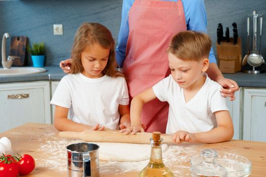 Young blonde woman, mother and her kids having fun while cooking dough close up