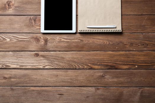 Top view of well organized home office workplace. Spiral notepad, pen and tablet computer on white surface. Education, creativity and working concept. Minimalist business design with copy space.