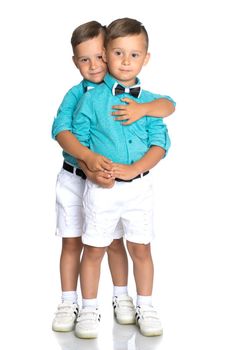 Two cute little boys stand in front of the camera in full growth. The concept of a happy childhood, the development of a child in the family. Isolated on white background.