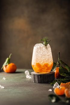 Fresh cocktail with crushed ice, rosemary and tangerines on the green table. Summer cold drink concept with copy space