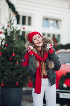 Belarus Minsk 16 12 2019:Beautiful winter young casual woman posing outdoor surrounded by snowflakes medium long shot. Happy beautiful girl enjoying Xmas mood at Christmas tree background having positive emotion