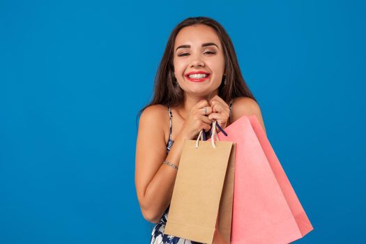 Photo of beautiful young woman with shopping bags on the wonderful blue background. The concept of shopping
