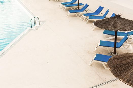 Hotel swimming pool with empty sun loungers.