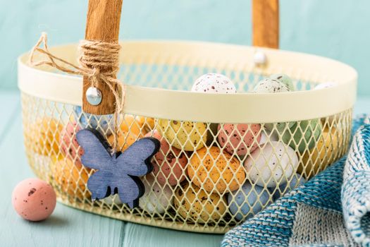 Metal basket with colourful Easter quail eggs. Spring holidays concept with copy space.