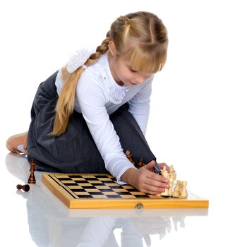 A little girl is playing chess. The concept of creative education of a child, training of thinking. Isolated on white background