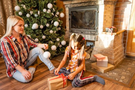 Mom and daughter playing with balls near the Christmas tree. gifts, lights, balls in the background.
