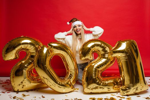 cheerful caucasian young woman in white sweater, blue jeans and red christmas hat, picture isolated on red background