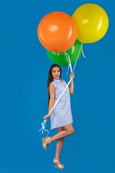 Full-length shot of smiling young woman looking camera and holding colorful air balloons isolated over blue. Conception of celebrations and birthday party