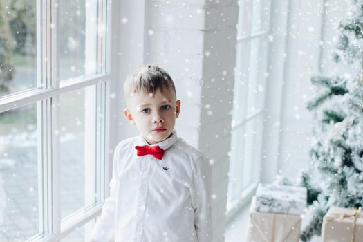 Happy child sits on the armchair in christmas atmosphere and smiles