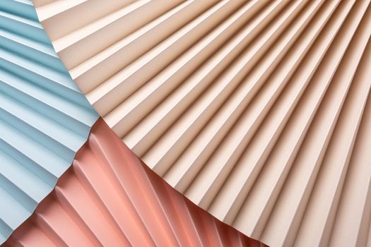 Colorful abstract background with paper fans, multicolored, light blue, pink and beige. Trend Concept. Top view, close up.