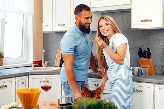 Happy smiling couple cooking food at kitchen with their dog