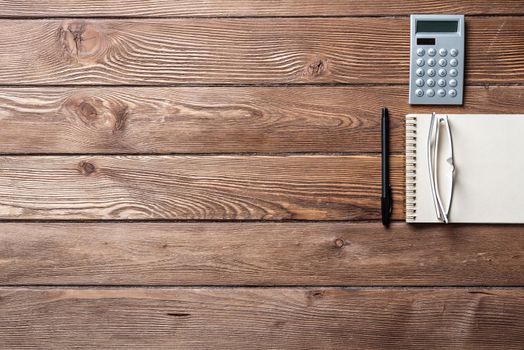 Still life of accountant vintage workspace with office accessories. Flat lay old hardwood desk with notepad, pen and calculator. Accounting and banking services. Finance and investment concept.