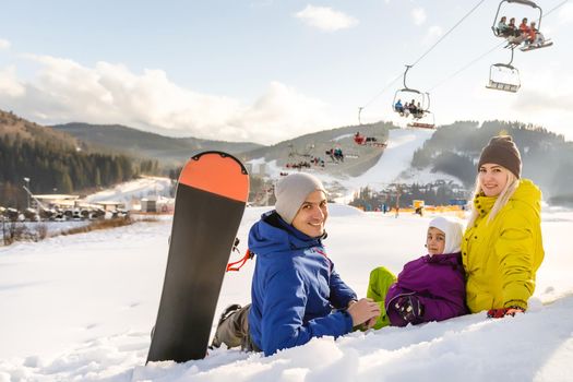 Mother and daughter with snowboards are playing in the snow