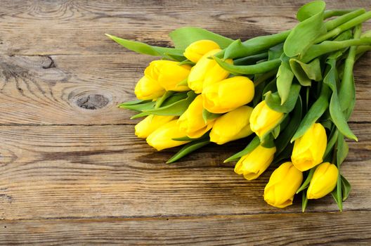 Yellow tulips lie on an old wooden surface. Studio Photo