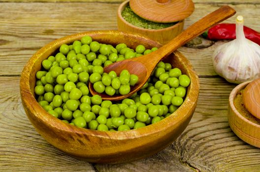 Wooden bowl with canned green peas on table. Studio Photo