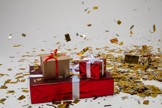 red and brown boxes with white tape with a presents in a beautiful pack with a lot of gold confetti around them