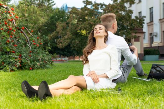 Business persons in the park sit on the grass in the park