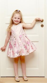 A nice little girl is standing by the door. The concept of family happiness and a home.