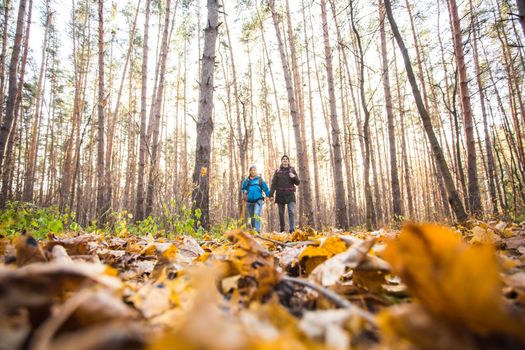 adventure, travel, tourism, hike and people concept - smiling couple walking with backpacks over autumn natural background.