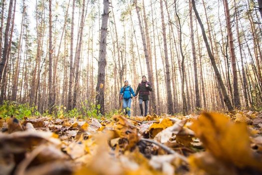 Adventure, travel, tourism, hike and people concept - smiling couple walking with backpacks over autumn natural background.