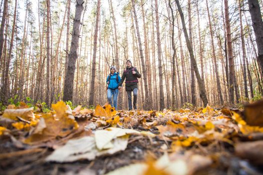 Adventure, travel, tourism, hike and people concept - smiling couple walking with backpacks over autumn natural background.