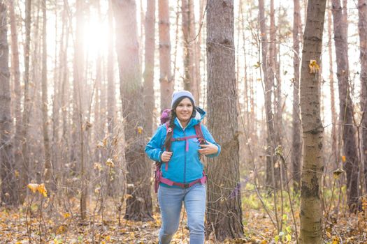 adventure, travel, tourism, hike and people concept - smiling tourist woman walking with backpacks over autumn natural background.