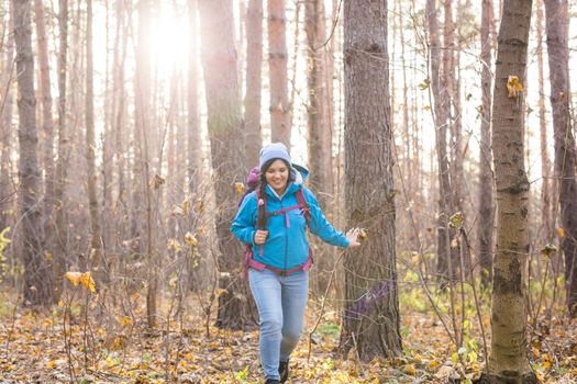 adventure, travel, tourism, hike and people concept - smiling tourist woman walking with backpacks over autumn natural background.