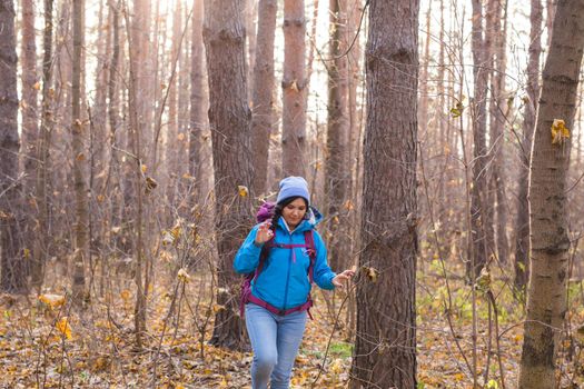 adventure, travel, tourism, hike and people concept - smiling tourist woman walking with backpacks over autumn natural background.