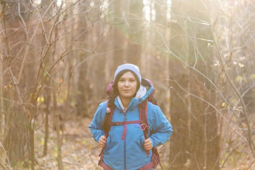 adventure, travel, tourism, hike and people concept - smiling woman walking with backpacks over autumn natural background.