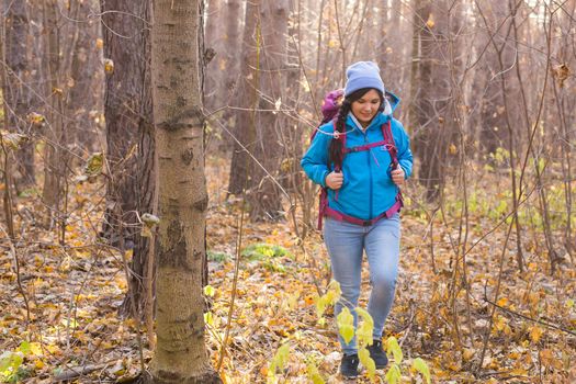 adventure, travel, tourism, hike and people concept - smiling tourist woman walking with backpacks over autumn natural background.