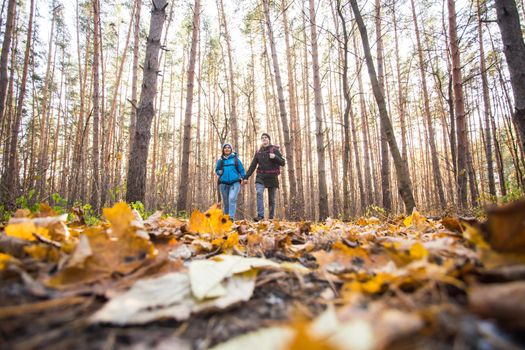 adventure, travel, tourism, hike and people concept - smiling couple walking with backpacks over autumn natural background.