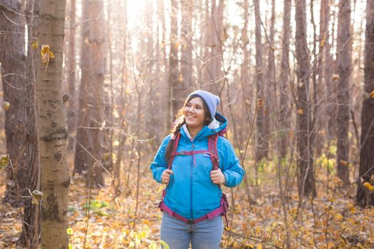 adventure, travel, tourism, hike and people concept - smiling tourist woman walking with backpacks over autumn natural background.