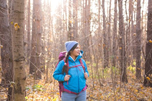 adventure, travel, tourism, hike and people concept - smiling tourist woman walking with backpacks over autumn natural background.