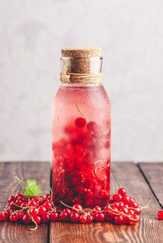 Red currant infused water with ice in glass bottle