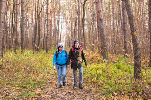 adventure, travel, tourism, hike and people concept - smiling couple walking with backpacks over autumn natural background.