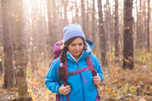 adventure, travel, tourism, hike and people concept - smiling tourist woman walking with backpacks over autumn natural background.