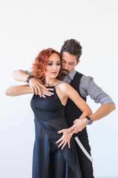 Social dance, bachata, kizomba, zouk, tango concept - Man hugs woman while dancing over white background in studio.