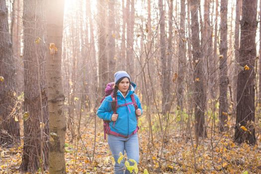 adventure, travel, tourism, hike and people concept - smiling woman walking with backpacks over autumn natural background.