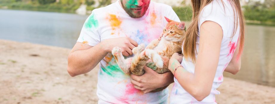 Pet, summer tourism, festival holi and nature concept - funny man and woman with cat on natural background.