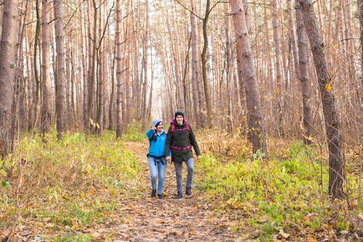 adventure, travel, tourism, hike and people concept - smiling couple walking with backpacks over natural background.
