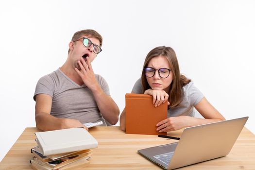 Education, people concept- a couple of young people in glasses look like they are bored of learning homework.