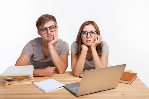 Education, people concept- a couple of young people in glasses look like they are bored of learning homework.