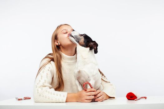 pretty young blond girl with her little cute dog wearing Santas red hat at Christmas holiday isolated on white background, lifestyle people concept close up